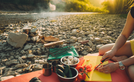 Matlagning vid vattnet på stenstrand. Grönsaker fungerar alltid i matlagning under camping!
